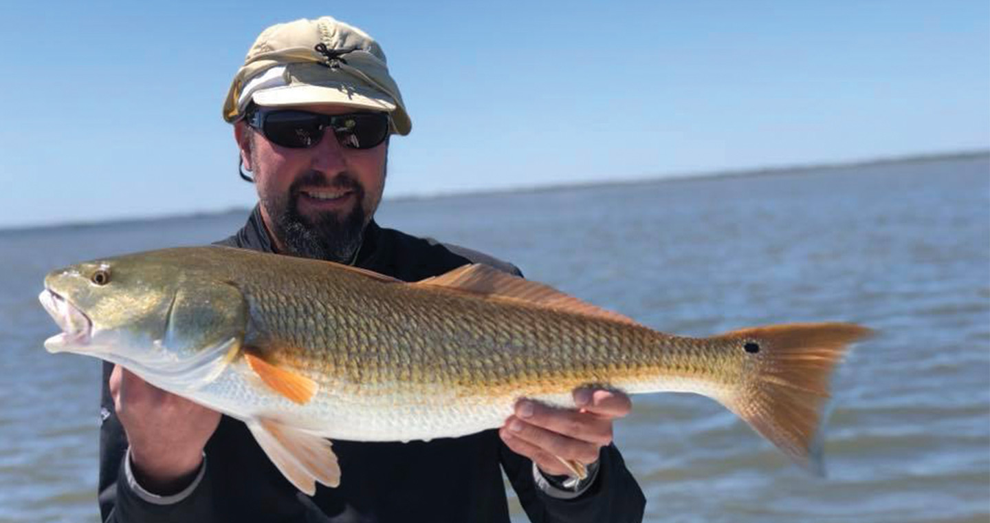 Man holding redfish at the Mosquito Lagoon Bay Fishing Charter